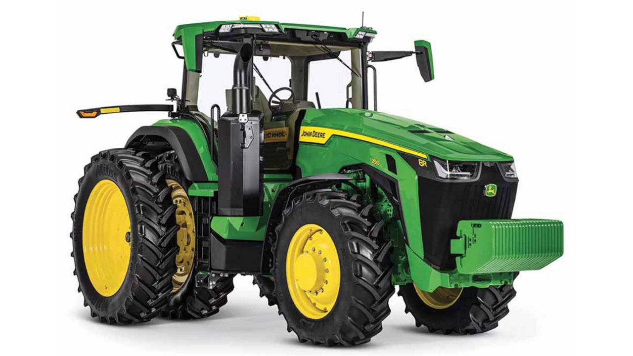 A midsized green John Deere tractor with large tires and a single man cabin. The tires have large yellow rims.